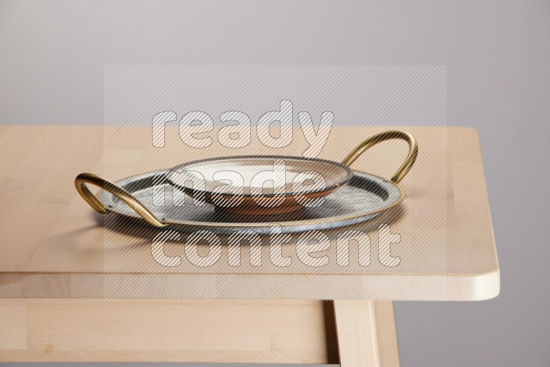 multicolored plate placed on a rounded stainless steel tray with golden handels on the edge of wooden table