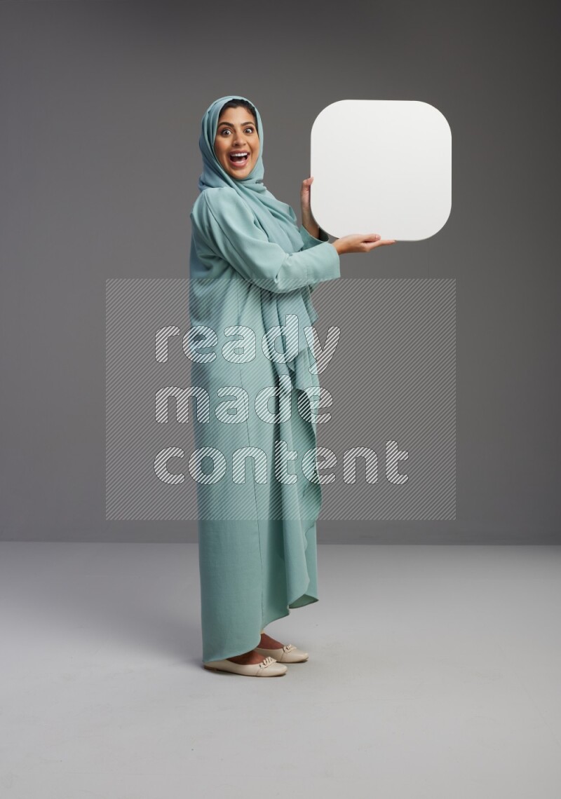 Saudi Woman wearing Abaya standing holding social media sign on Gray background