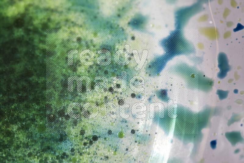 لقطات مقربة لقطرات ألوان مائية خضراء وزرقاء على سطح الزيت على خلفية بيضاء