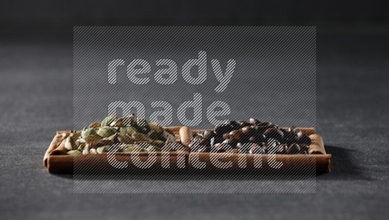 مربعان من أعواد القرفة ممتلئان بحبوب القهوة وحبوب الهيل علي خلفية سوداء