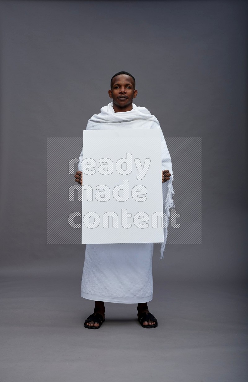 A man wearing Ehram Standing holding board sign on gray background