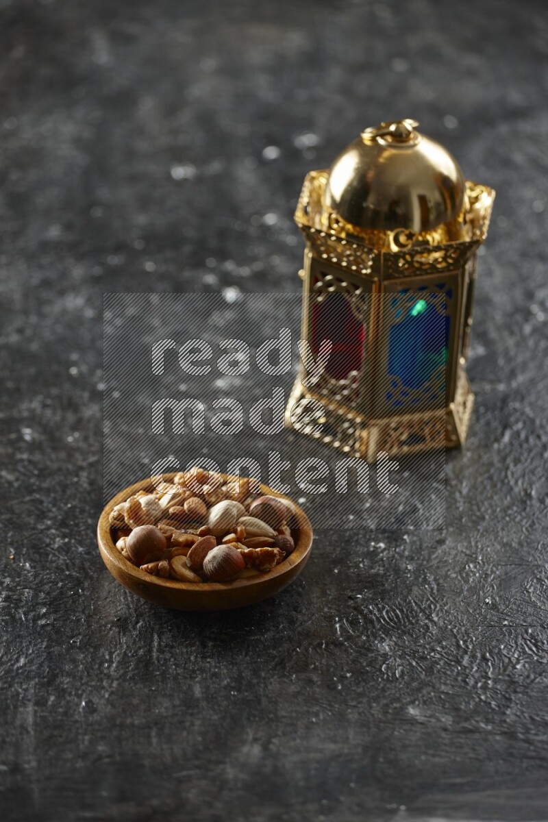 A golden lantern with different drinks, dates, nuts, prayer beads and quran on textured black background