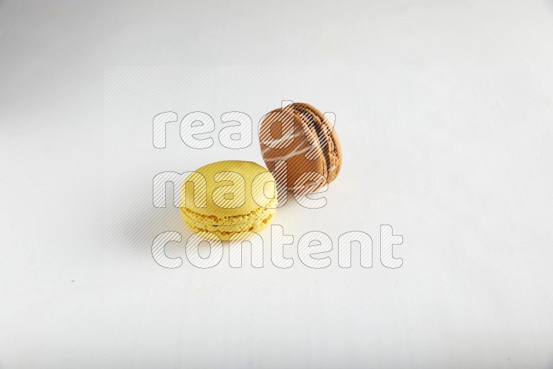 45º Shot of of two assorted Brown Irish Cream, and Yellow Lemon macarons on white background