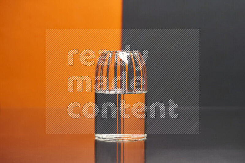 The image features a clear glassware filled with water, set against orange and black background