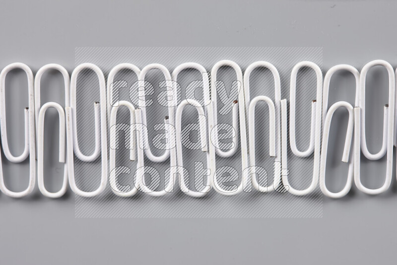 White paper clips isolated on a grey background