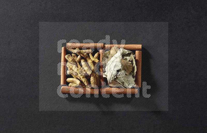2 squares of cinnamon sticks full of bay laurel leaves and turmeric fingers on black flooring