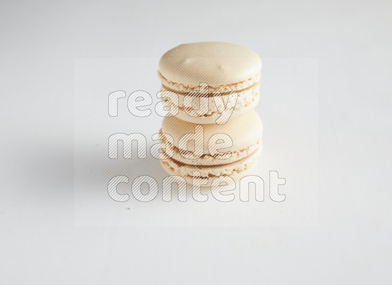45º Shot of two White Caramel fleur de sel macarons on white background