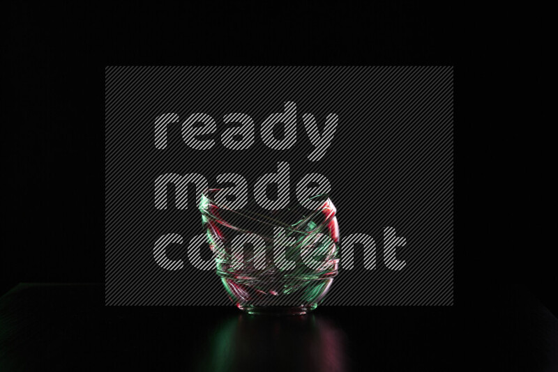 Glassware with rim light in red and green against black background