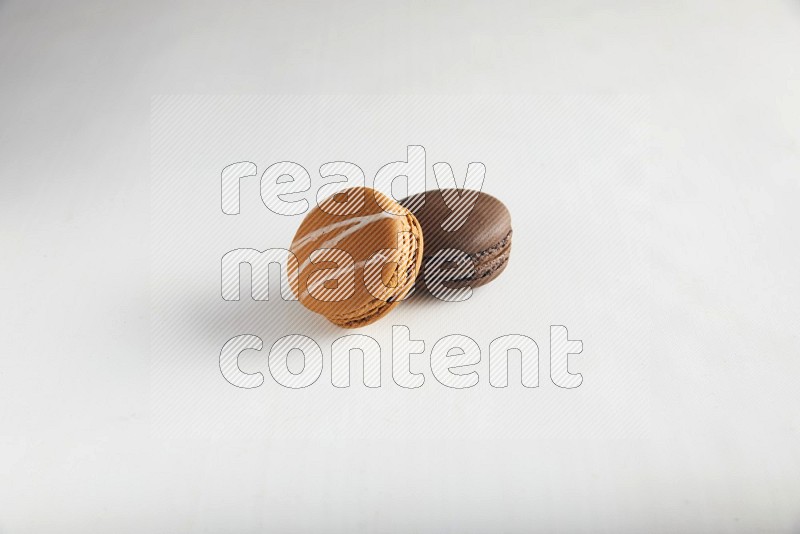 45º Shot of of two assorted Brown Irish Cream, and Brown Dark Chocolate macarons on white background