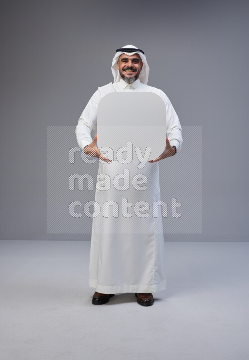 Saudi man Wearing Thob and white Shomag standing holding social media sign on Gray background