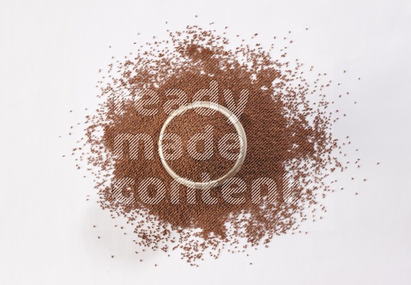 وعاء فخاري بيج ممتلئ ببذور حب الرشاد مع بعض البذور متناثرة على خلفية بيضاء