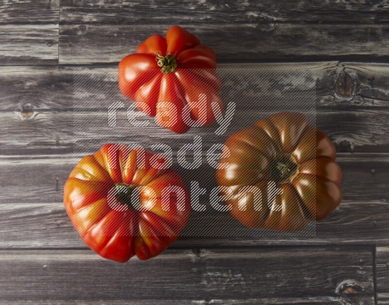 three heirloom tomatoes topview on a textured vinyl background