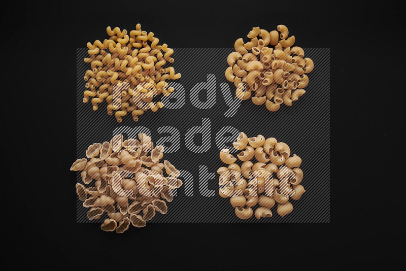 Different pasta types in bunches on black background