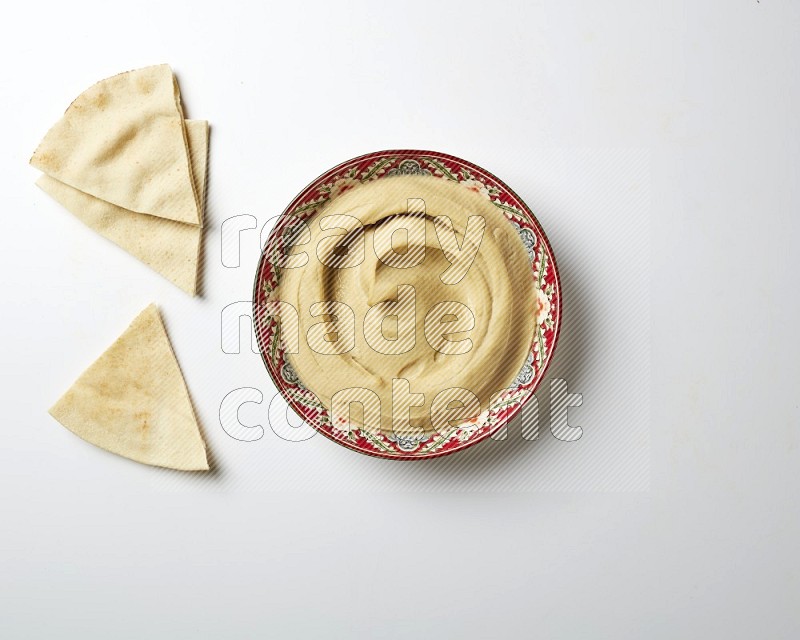 Plain Hummus in a red plate with patterns on a white background