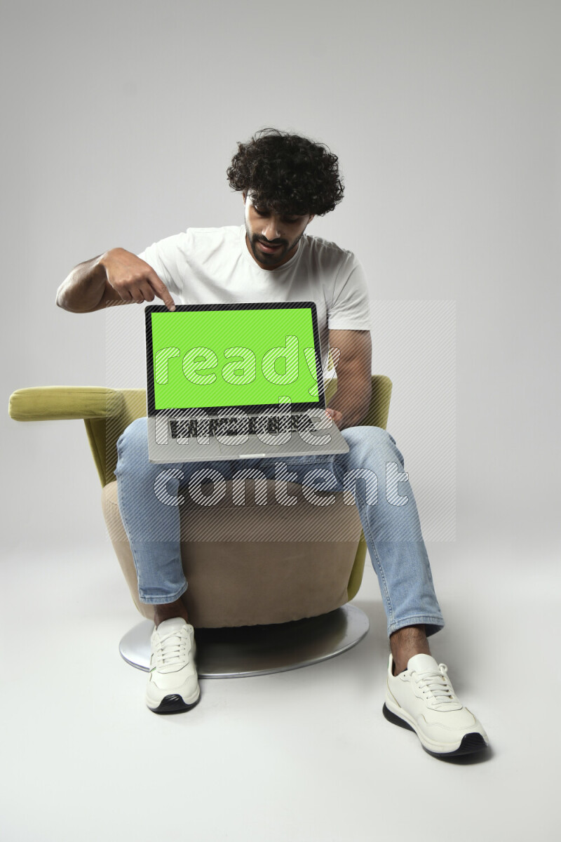 A man wearing casual sitting on a chair showing a laptop screen on white background