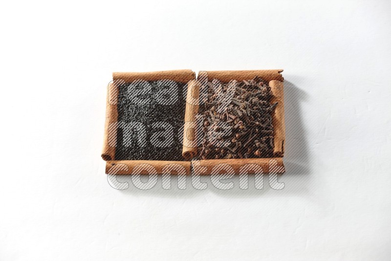 2 squares of cinnamon sticks full of cloves and black seeds on white flooring