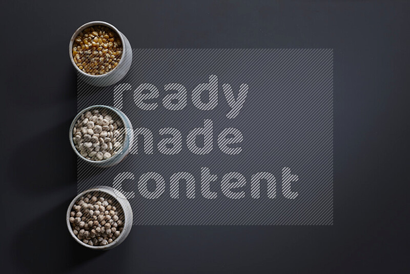 Legumes in pottery bowls on grey background