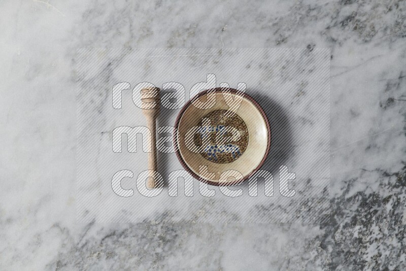 Decorative pottery plate with wooden honey dipper on the side on grey marble background