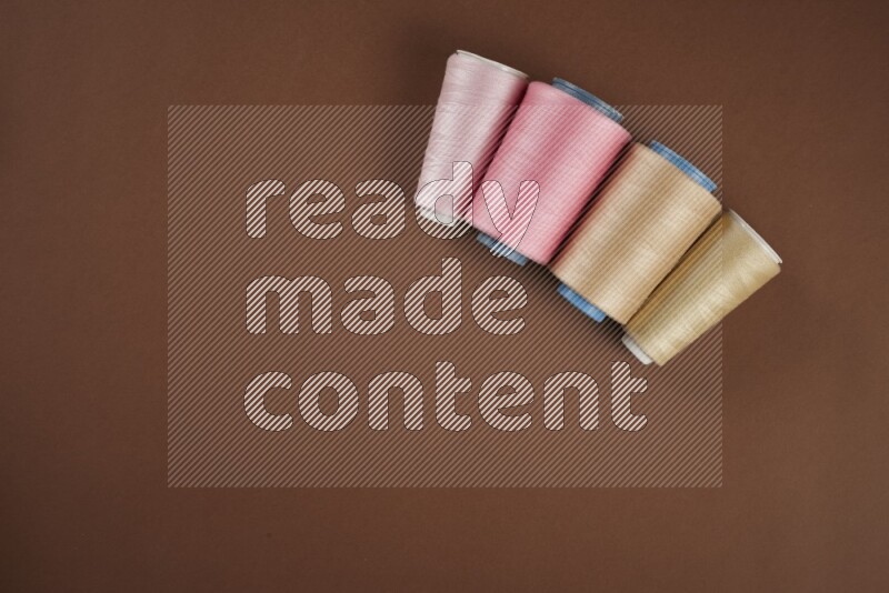 A pink collection of sewing and tailoring tools arranged on a brown background