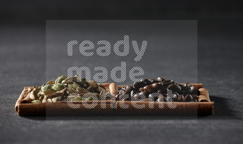 مربعان من أعواد القرفة ممتلئان بحبوب القهوة وحبوب الهيل علي خلفية سوداء