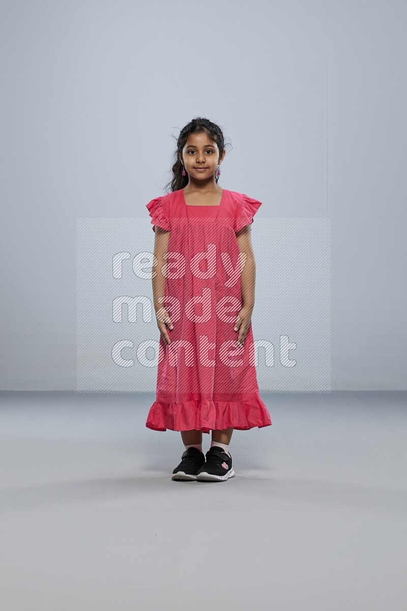 A girl standing interacting with the camera on gray background