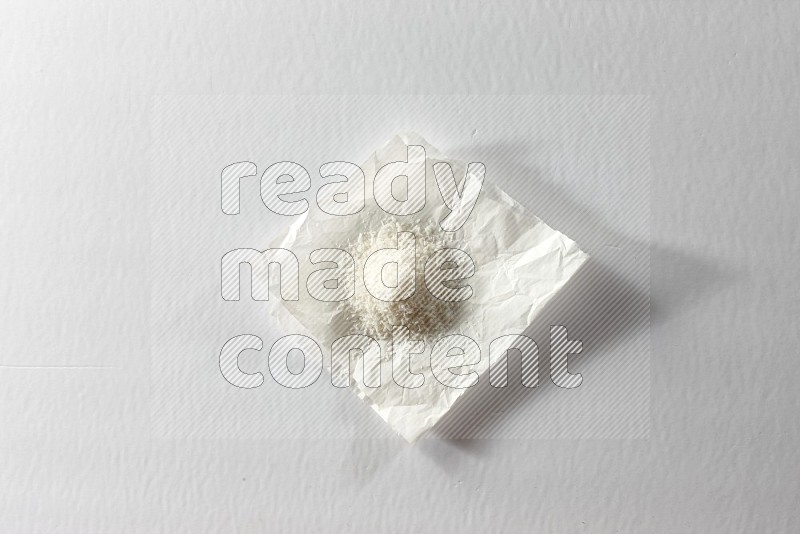جوز الهند المجفف المبشور على قطعة من الورق على خلفية بيضاء