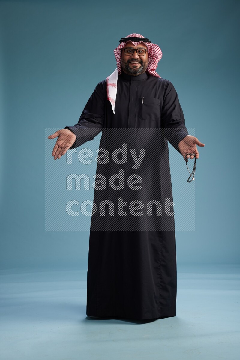 Saudi Man with shimag Standing Interacting with the camera on blue background