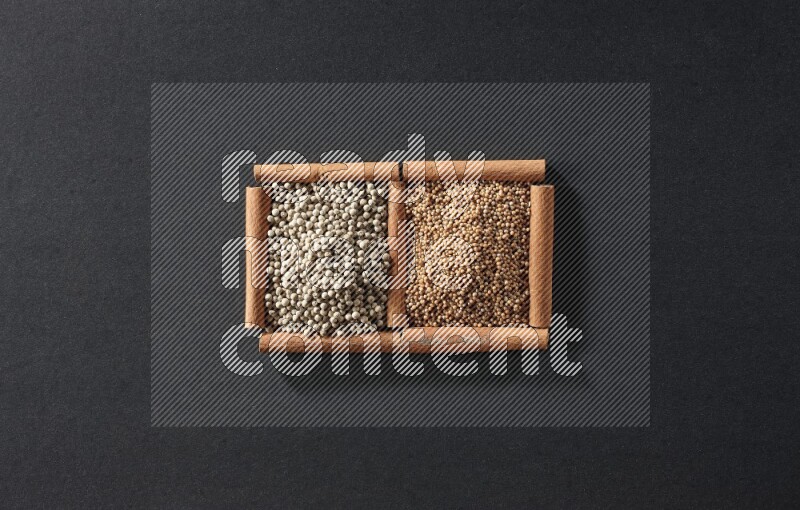 مربعان من أعواد القرفة ممتلئان بحبوب الخردل وحبوب الفلفل الأبيض علي خلفية سوداء