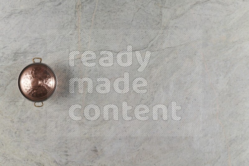 A small copper pot on grey marble background