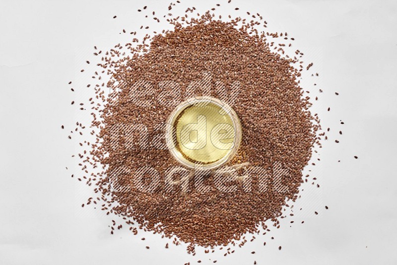 A glass jar full of flax oil surrounded by flax seeds on a white flooring in different angles