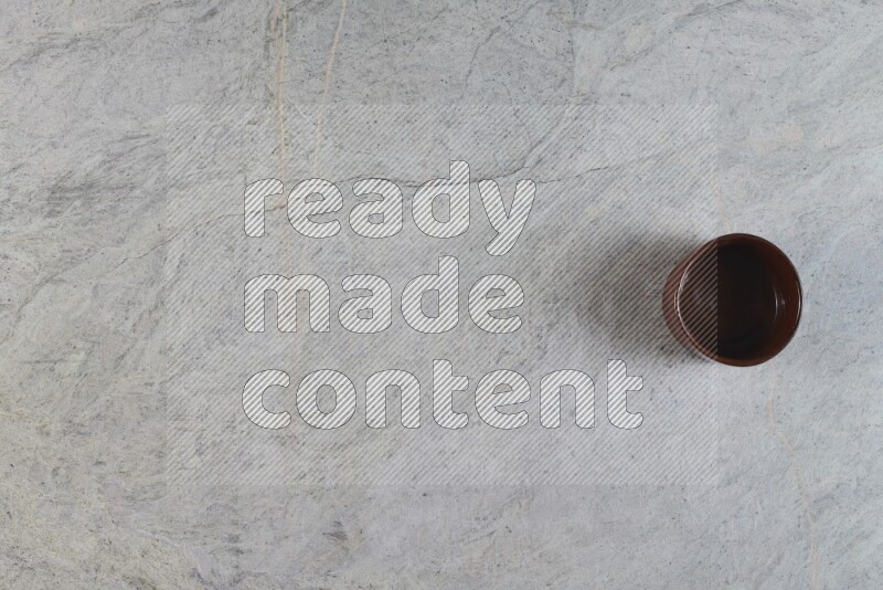 A brown pottery bowl on grey marble background