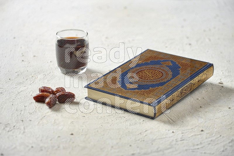 Quran with dates, prayer beads and different drinks on textured white background