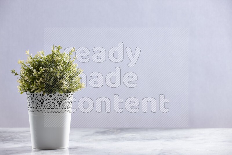 Artificial plant in white decorative pot on grey marble background