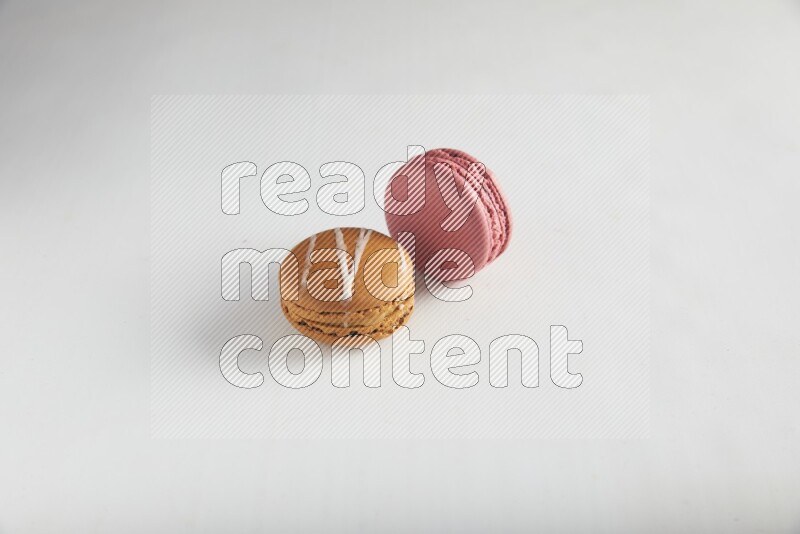 45º Shot of of two assorted Brown Irish Cream, and Pink Raspberry macarons on white background