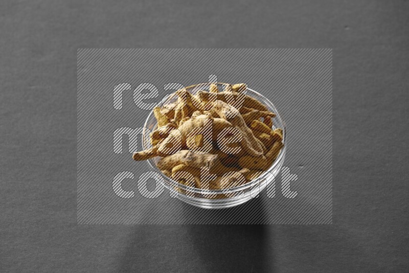 A glass bowl full of turmeric on black flooring