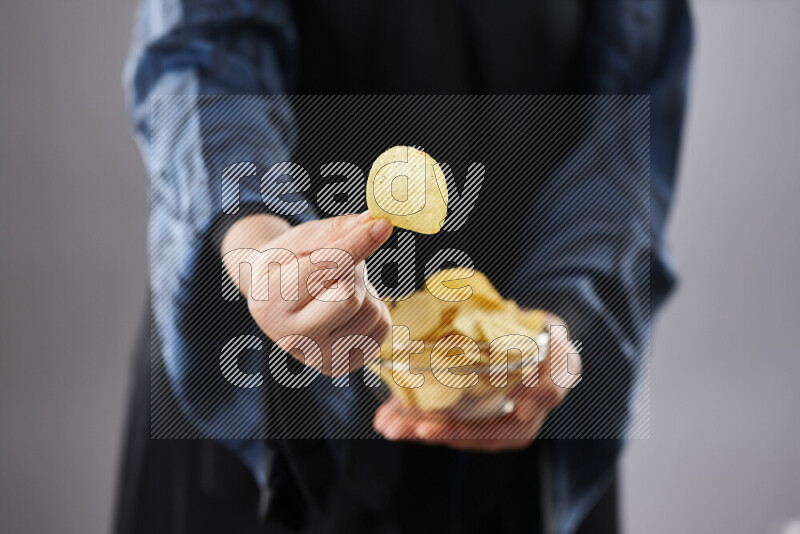 Woman in abaya holding different kinds of snacks in different positions
