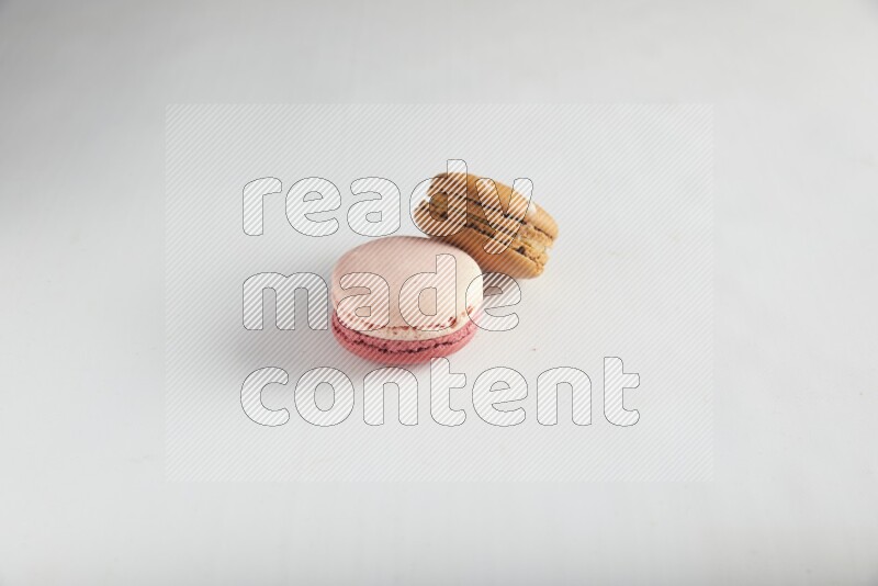 45º Shot of of two assorted Brown Irish Cream, and Pink Litchi Raspberry macarons on white background