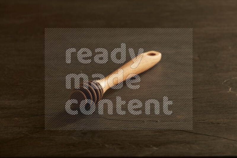Wooden honey dipper on black slate background