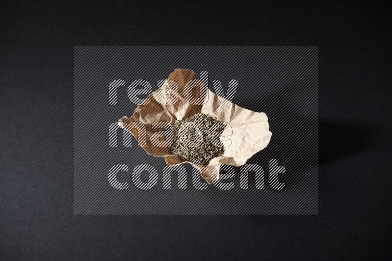 حبوب الكمون في قطعة من الورق على خلفية سوداء