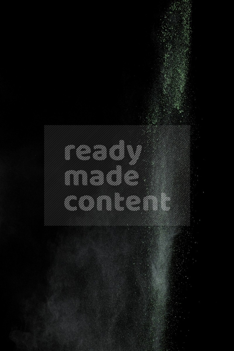 A side view of green powder explosion on black background