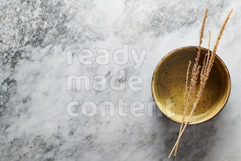 Wheat stalks on Multicolored Pottery Oven Plate on grey marble flooring, Top view