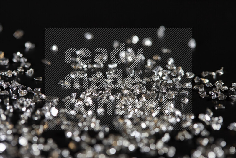 Silver shimmering fragments of glass scattered on a black background