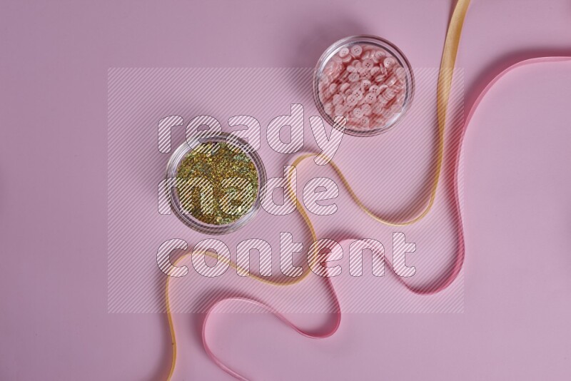 A yellow and pink collection of sewing and tailoring tools arranged on a pink background