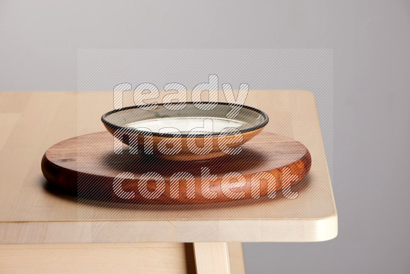 multi-colored pottery Plate placed on a dark colored wooden tray on the edge of wooden table