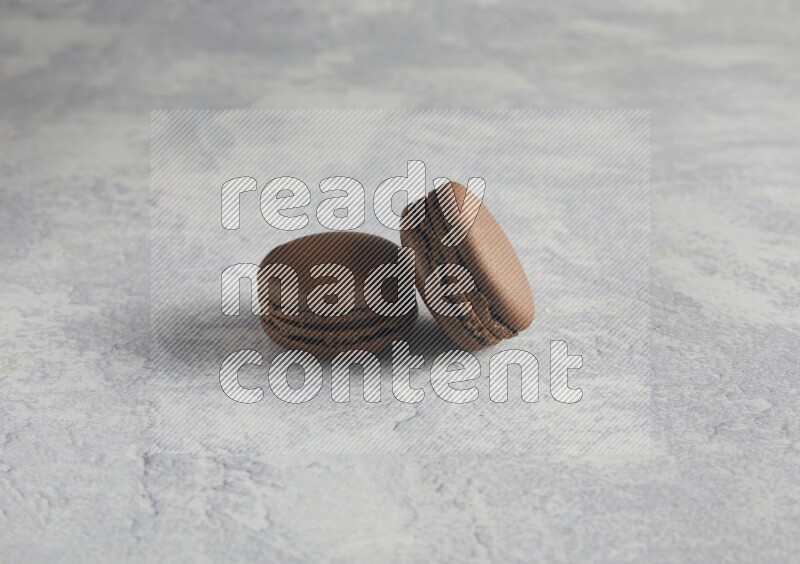 45º Shot of two Brown Dark Chocolate macarons  on white  marble background