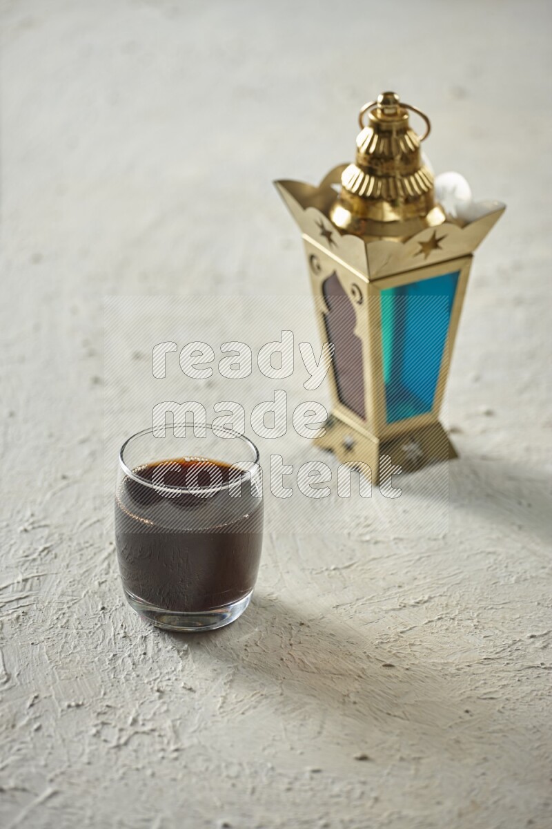 A golden lantern with different drinks, dates, nuts, prayer beads and quran on textured white background