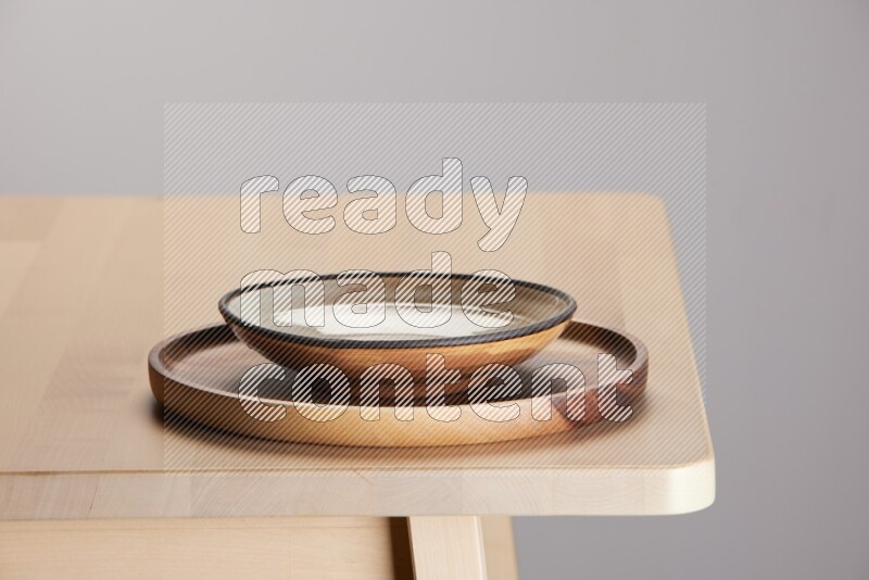 multi-colored pottery Plate placed on a light colored wooden tray on the edge of wooden table