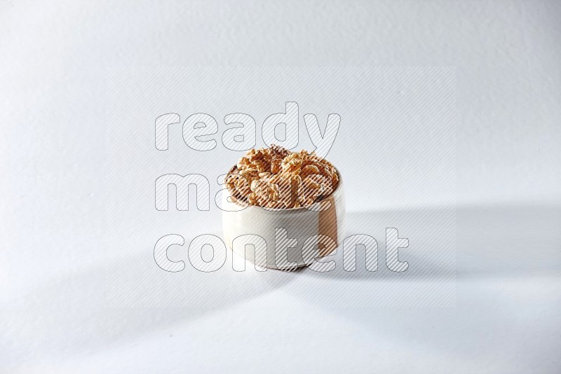 A beige ceramic bowl full of peeled walnuts on a white background in different angles