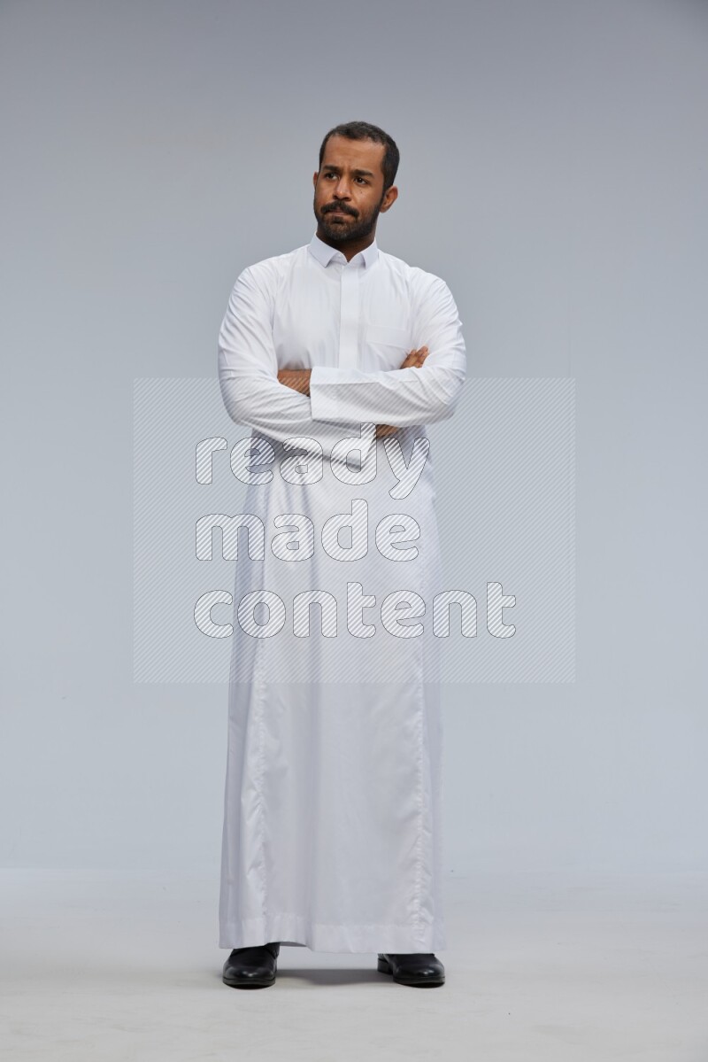 Saudi man wearing Thob standing with crossed arms on Gray background
