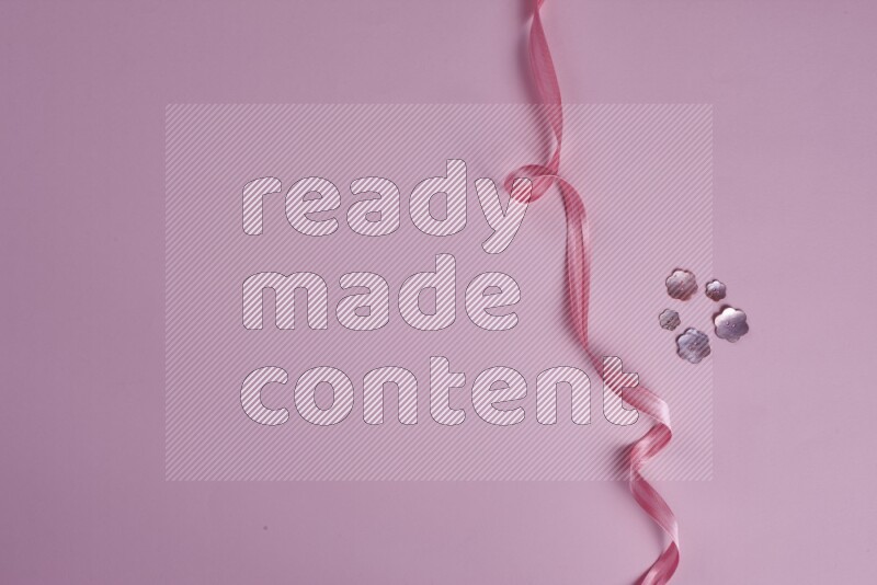 A pink collection of sewing and tailoring tools arranged on a pink background